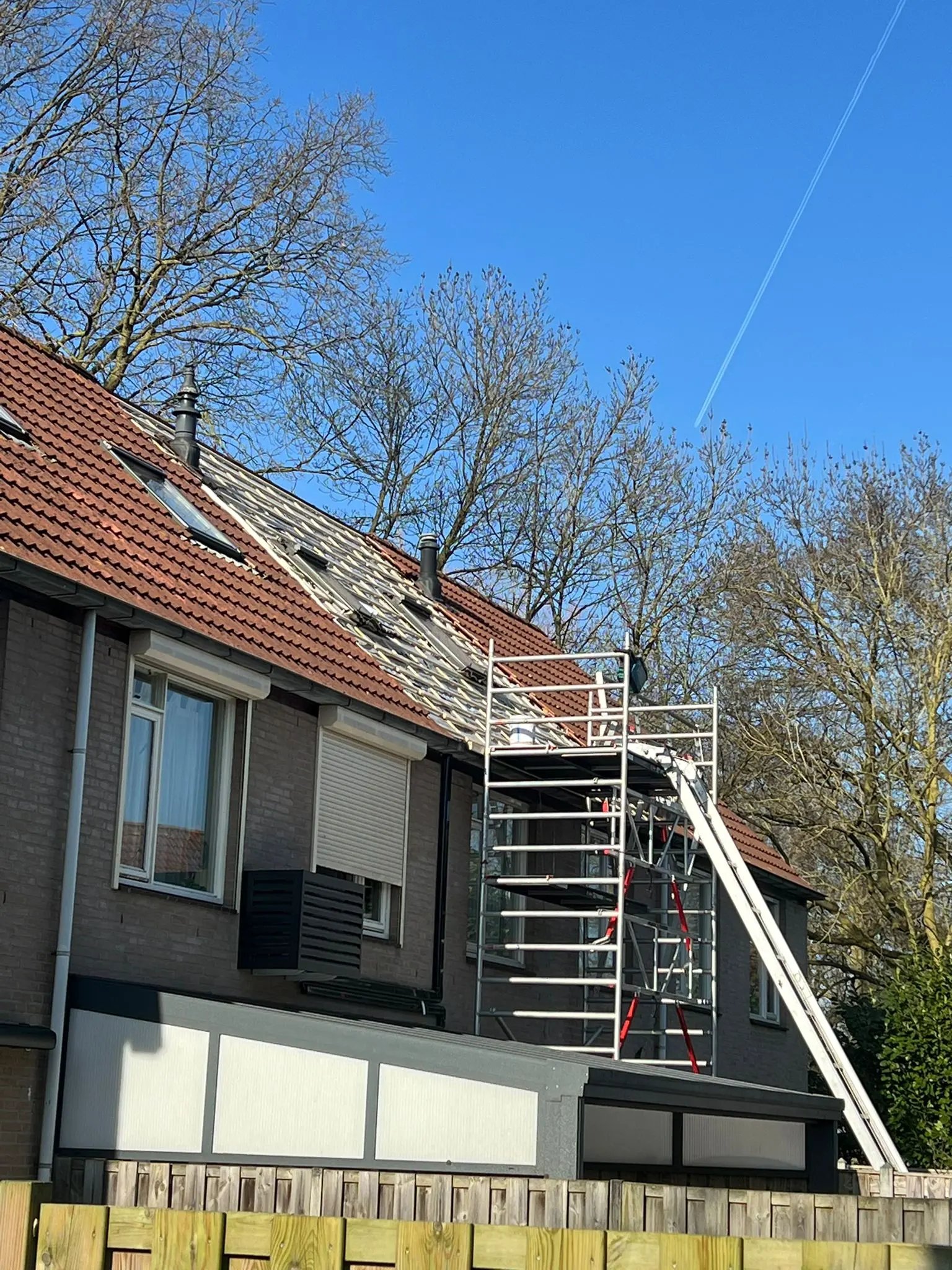 Half gestript pannendak met steiger en ladderlift tijdens een dakrenovatie