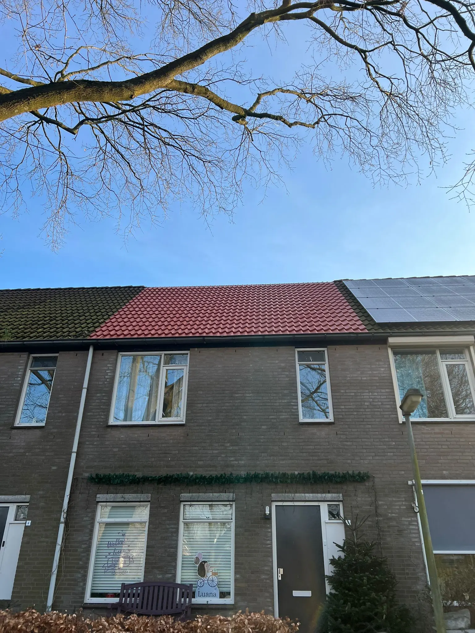 Rijtjeswoning met een nieuw rood pannendak tussen twee oudere daken