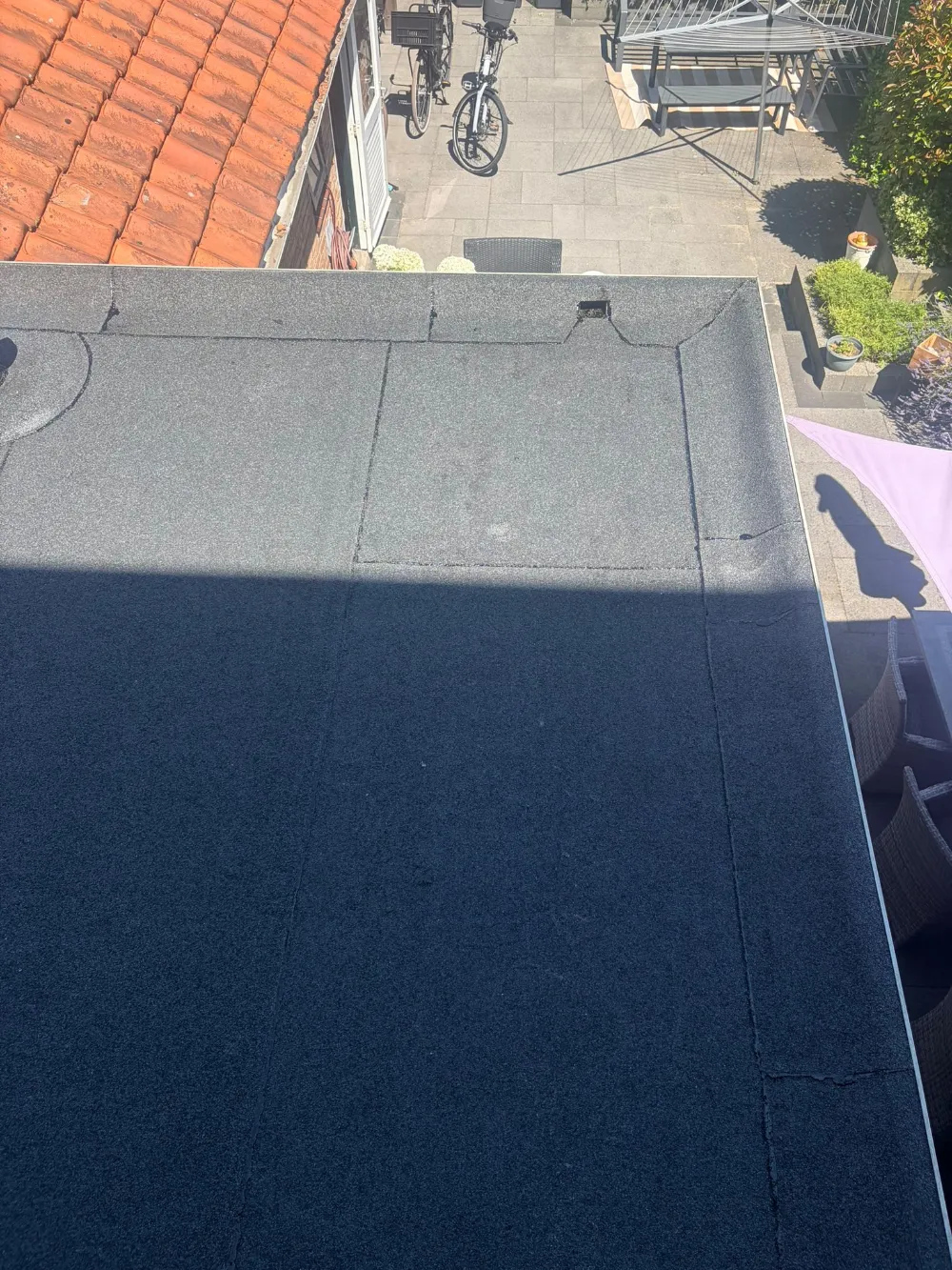 Bovenaanzicht van een afgerond grijs plat dak boven een achtertuin