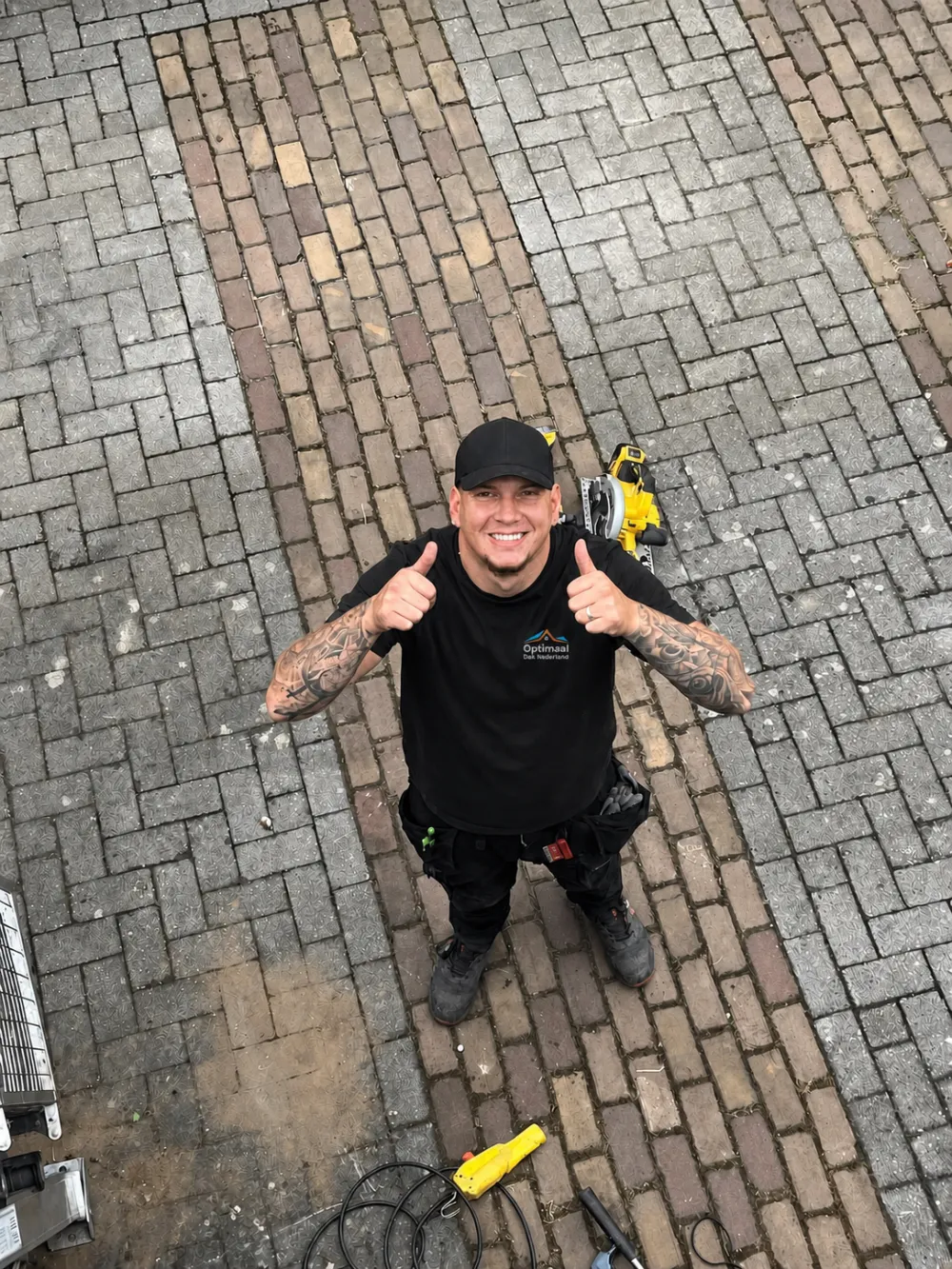 Lachende dakdekker in een shirt met het logo van Optimaal Dak steekt zijn duim op