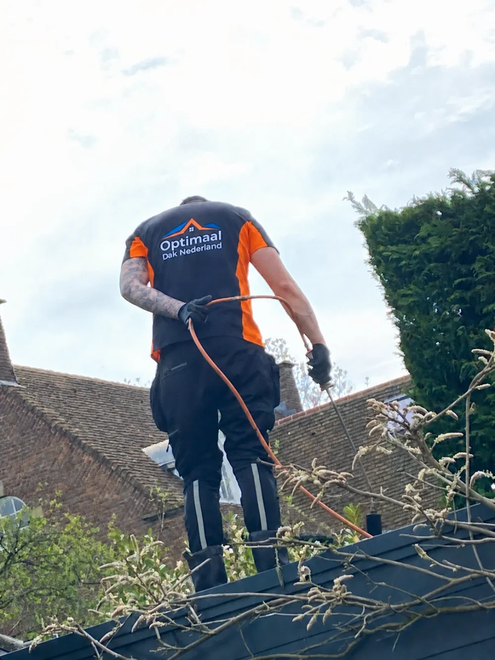 Dakdekker van Optimaal Dak aan het werk met een brander, van onderaf gezien tegen de lucht